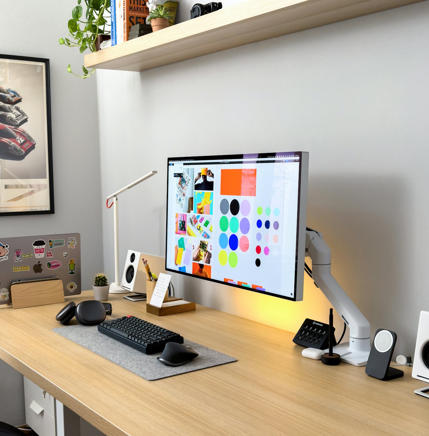 Moderní kancelářský stůl s počítačem, notebookem a designovým softwarem.