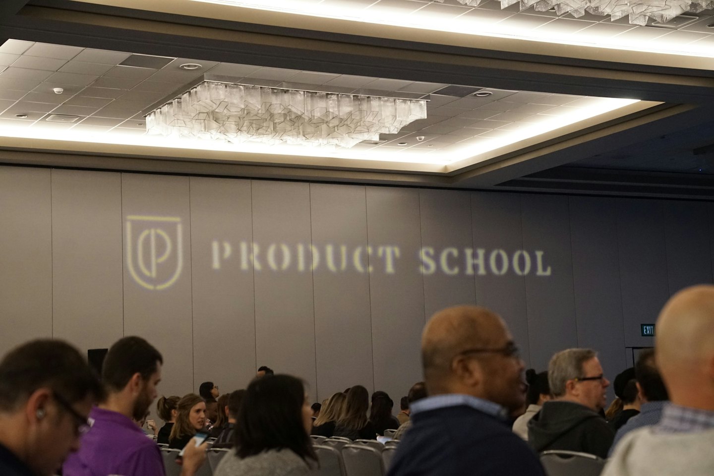 Dospělí poslouchají prezentaci na konferenci Product School.
